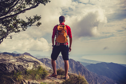 A runner pauses to take in the summit overlook while wearing a backpack.